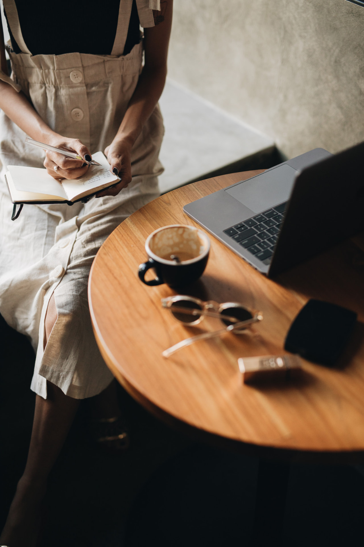 Professional writing notes beside a laptop and coffee