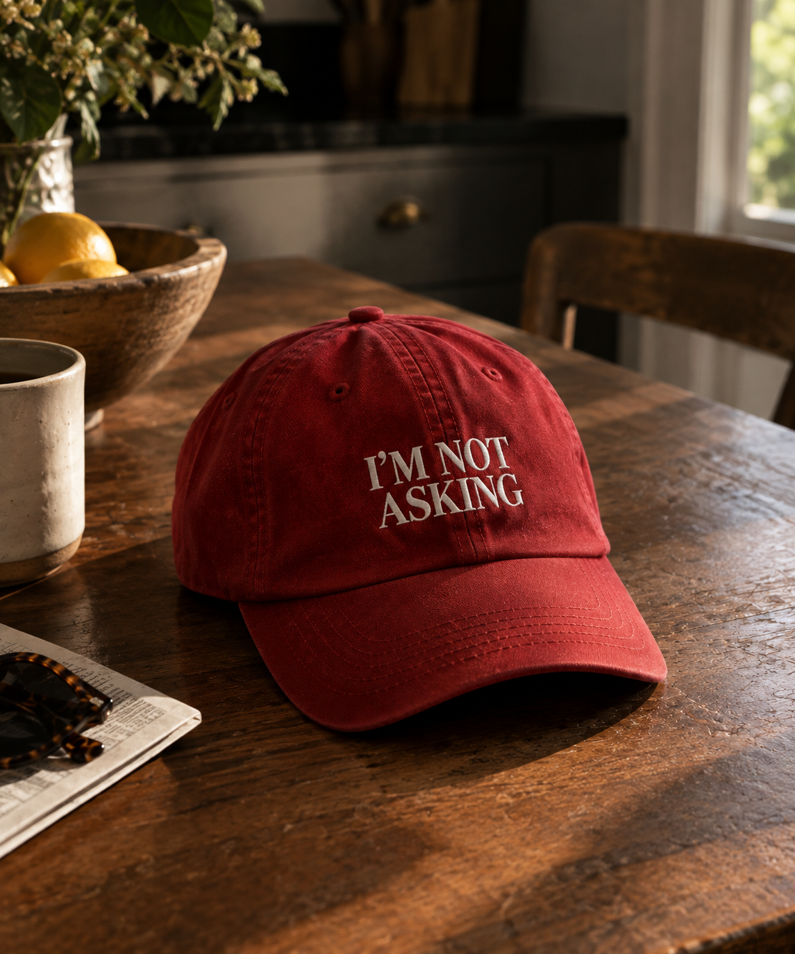 Red Divorce Season cap with I'M NOT ASKING on a wooden table